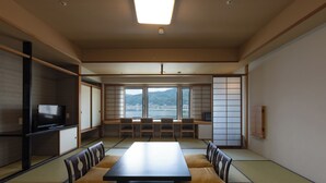A traditional Japanese room with tatami flooring, a low table, cushions, and a television. - Rako Hananoi Hotel (Suwa)