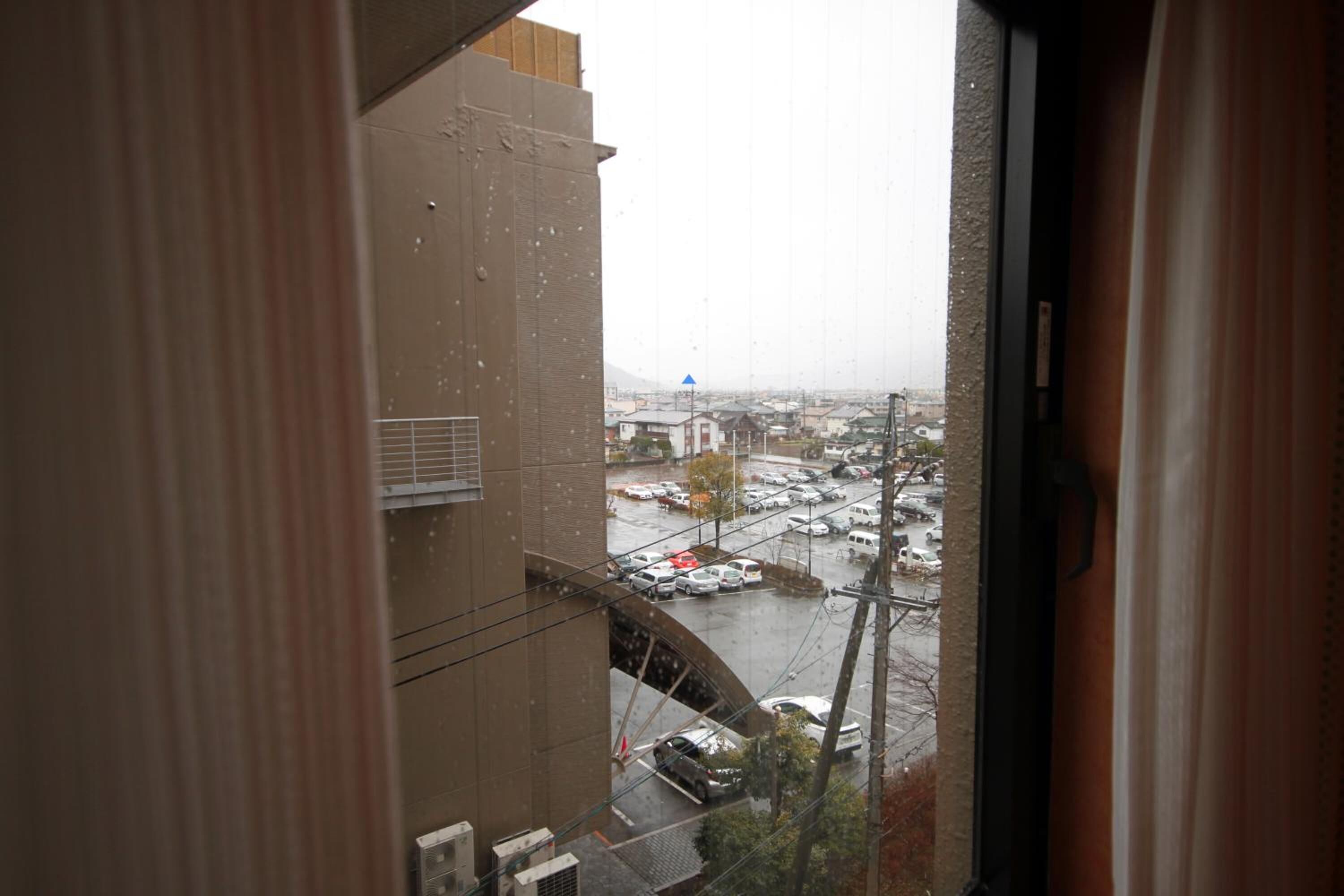 A view through a window of a building with a view of a cityscape, including a bridge and parked cars.