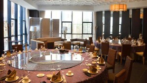 A dining area with round tables set for a meal, large windows, and a high ceiling with a unique pattern. - Louguan Yinxiang Hotel Xi'an (Xi'an)