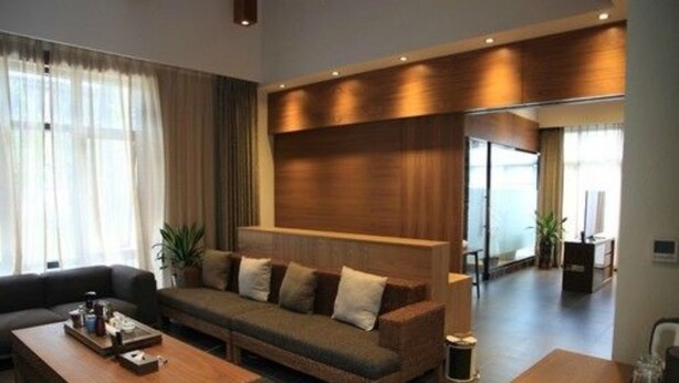 A modern living room with a sofa, coffee table, and a wooden accent wall. - Louguan Yinxiang Hotel Xi'an (Xi'an)