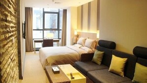 A hotel room with a large bed, a sofa, a desk, and a view of the city through large windows. - Louguan Yinxiang Hotel Xi'an (Xi'an)