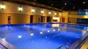 A large indoor swimming pool with clear blue water, surrounded by walls with light fixtures and a door leading to another room. - Louguan Yinxiang Hotel Xi'an (Xi'an)