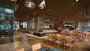 A spacious restaurant with wooden flooring, a central bar area, and multiple seating arrangements. - Yunkai Hotel (Guangzhou)