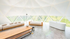 A modern interior with a large skylight, a wooden bench, a sofa, and a bathtub. - Planet Zero Retreat (Huzhou)