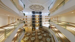 Een ruime atrium met meerdere niveaus, een centrale trap en tal van tafels op het laagste niveau.