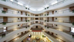 Een meerlaags atrium met een open centrale ruimte, balkons met beplanting en een modern architectonisch ontwerp.