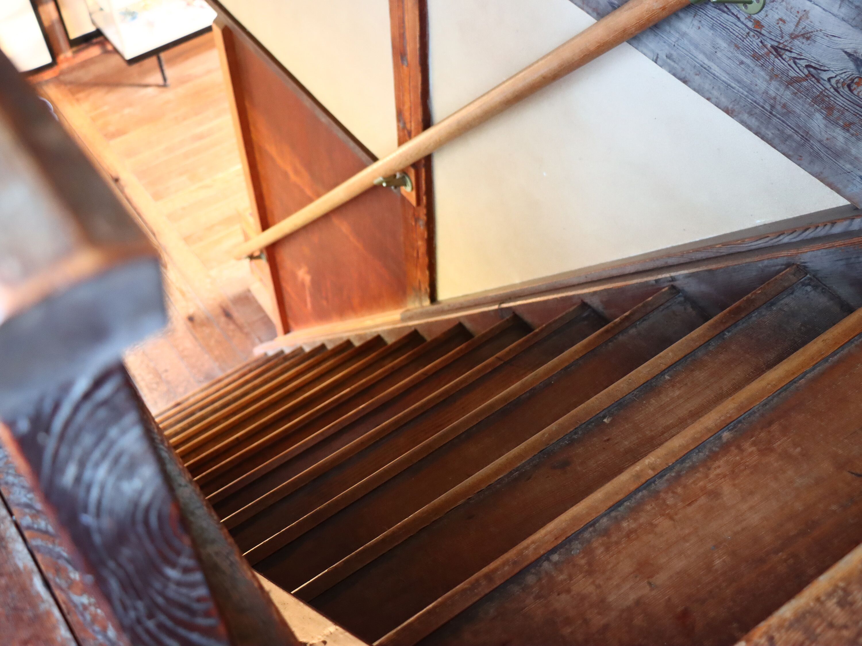 A wooden staircase with a handrail and a wooden floor.