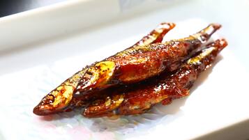 A plate with grilled fish, possibly marinated, on a patterned plate.