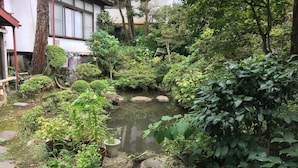 A traditional Japanese garden with a koi pond, surrounded by various plants and rocks. - Maruka Ryokan (Yamanouchi)
