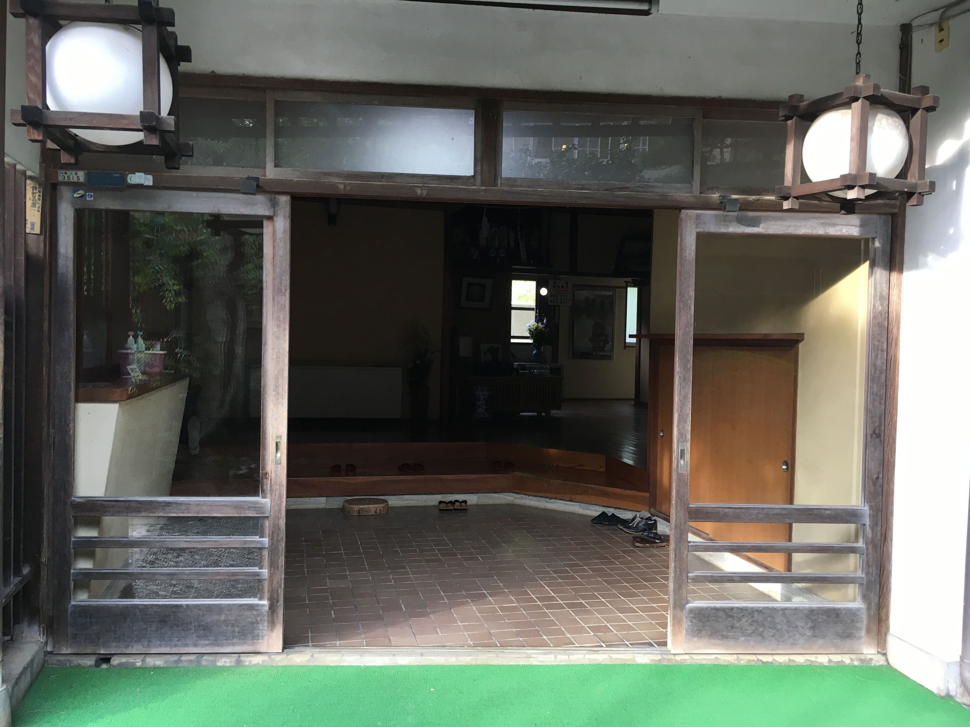 Una habitación con alfombra verde, piso de madera y un ventanal grande.