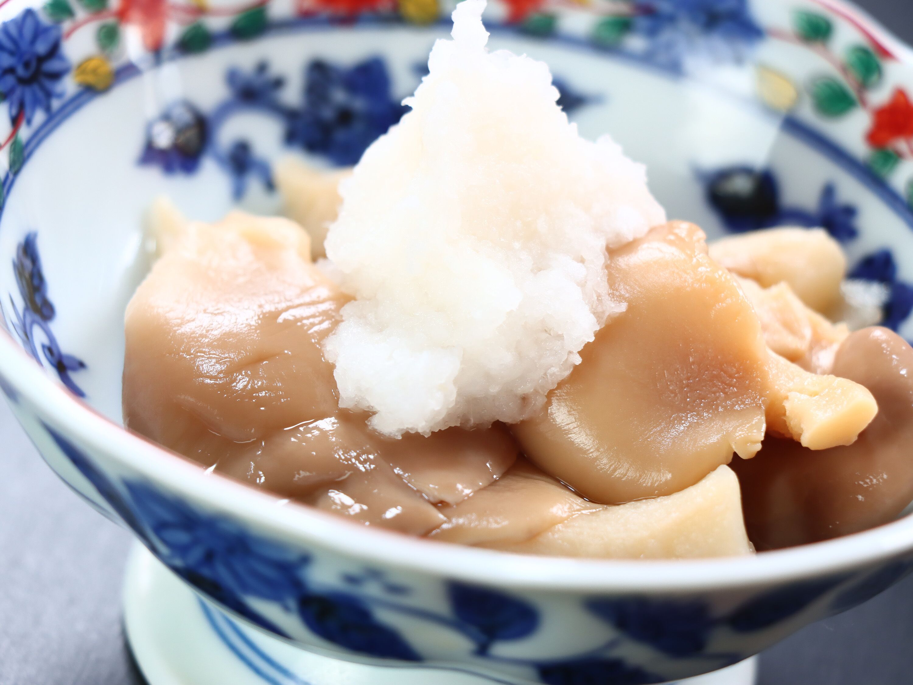 A bowl of food with a white topping, possibly ice cream or shaved ice, and a blue and white patterned bowl.