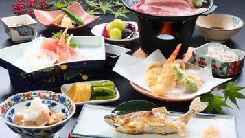 Diversos pratos japoneses, incluindo sushi, tempura e peixe grelhado, dispostos sobre uma mesa.