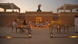 A group of people seated in a semi-circular arrangement on a stone patio with lanterns, under a large tent structure. - SUJÁN The Serai, Jaisalmer - Relais & Chateaux (Jaisalmer)