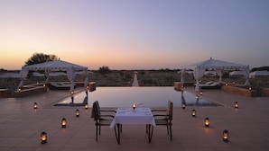 A serene outdoor dining area with a table set for two, surrounded by lanterns and under white canopies. - SUJÁN The Serai, Jaisalmer - Relais & Chateaux (Jaisalmer)