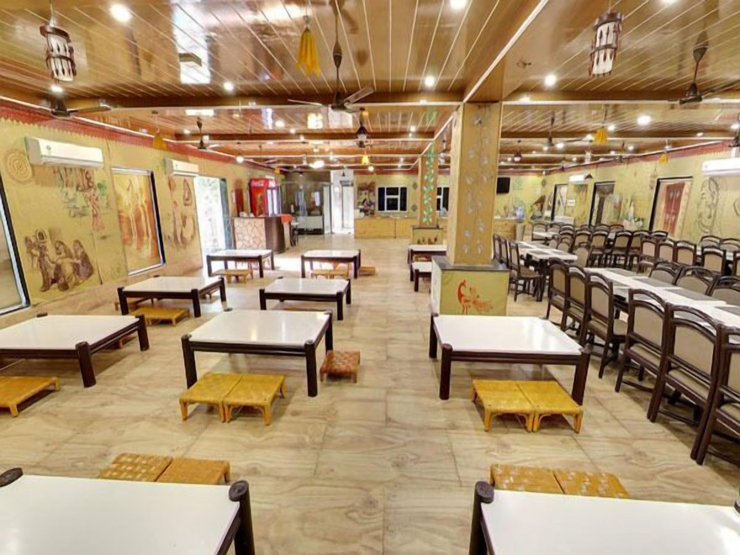 A restaurant with wooden tables and benches, artwork on the walls, and a tiled floor.