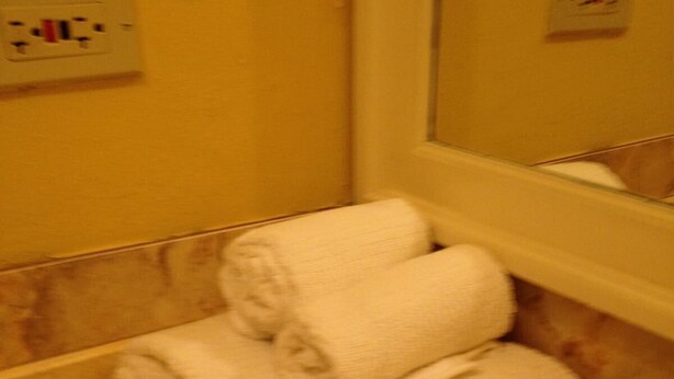 A bathroom with a marble wall, a towel rack with two towels, and a mirror. - Casa Royale Guest Apartment (Kingston)