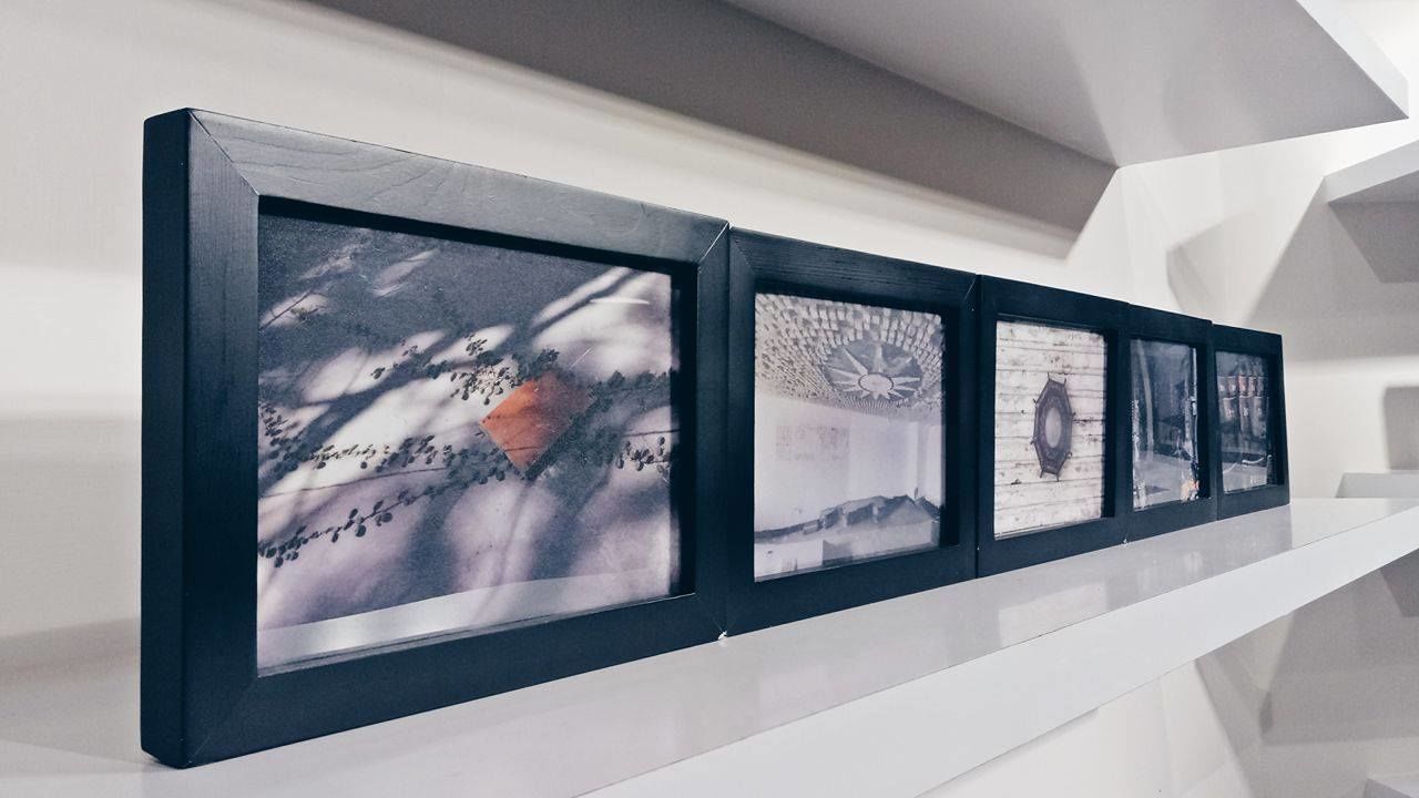 Varias obras de arte enmarcadas expuestas en una pared blanca dentro de una galería.