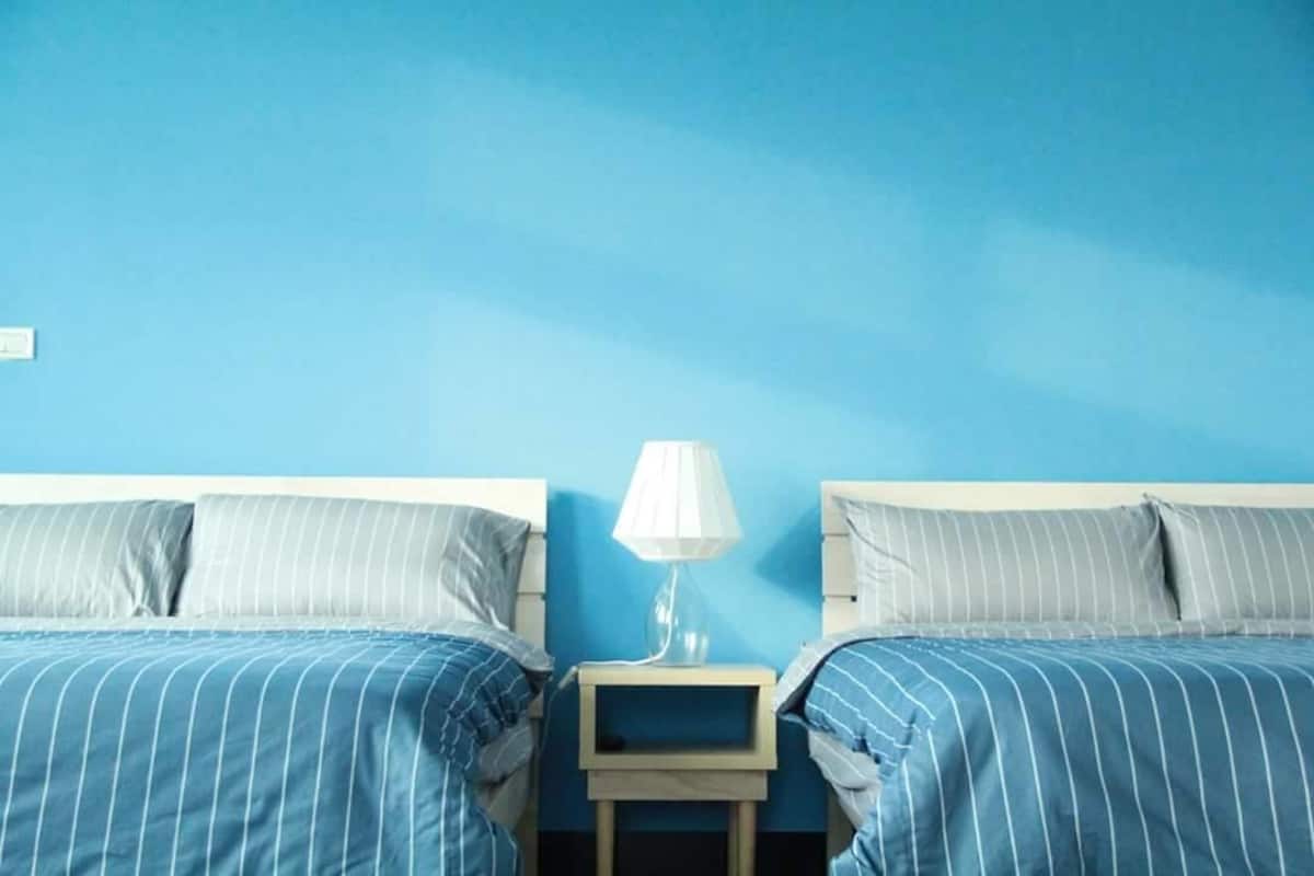 A bedroom with two beds, a nightstand, and a lamp.