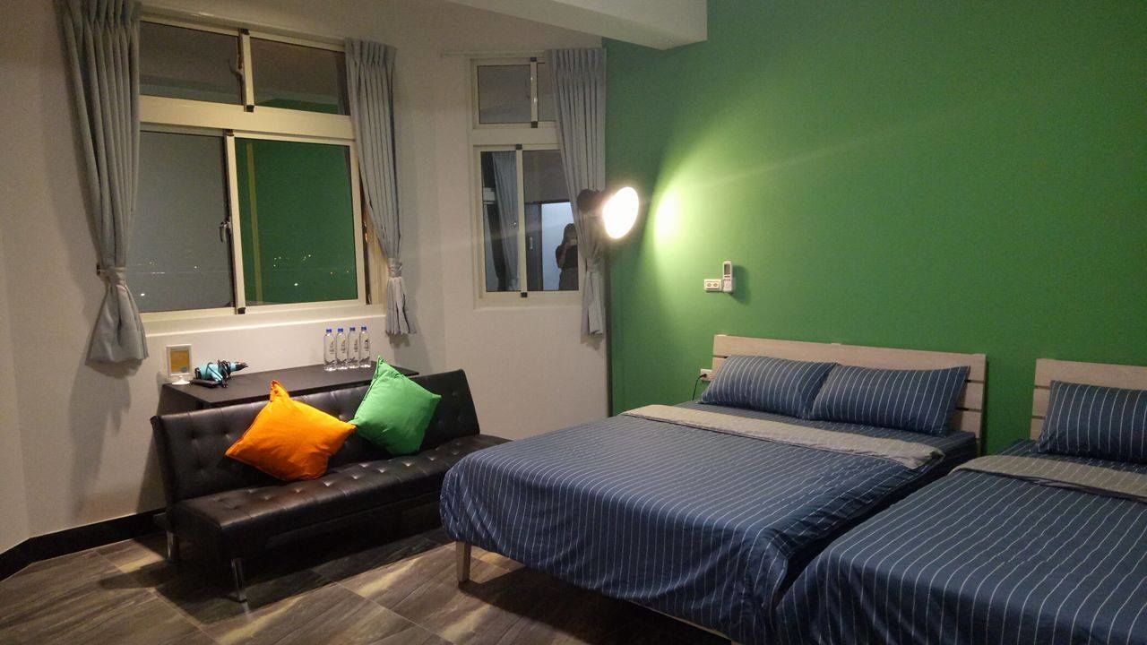 A room with two beds, a sofa, and a window with curtains.