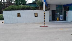Un edificio con recepción, aparcamiento y una pared de ladrillo blanco con paneles decorativos.
