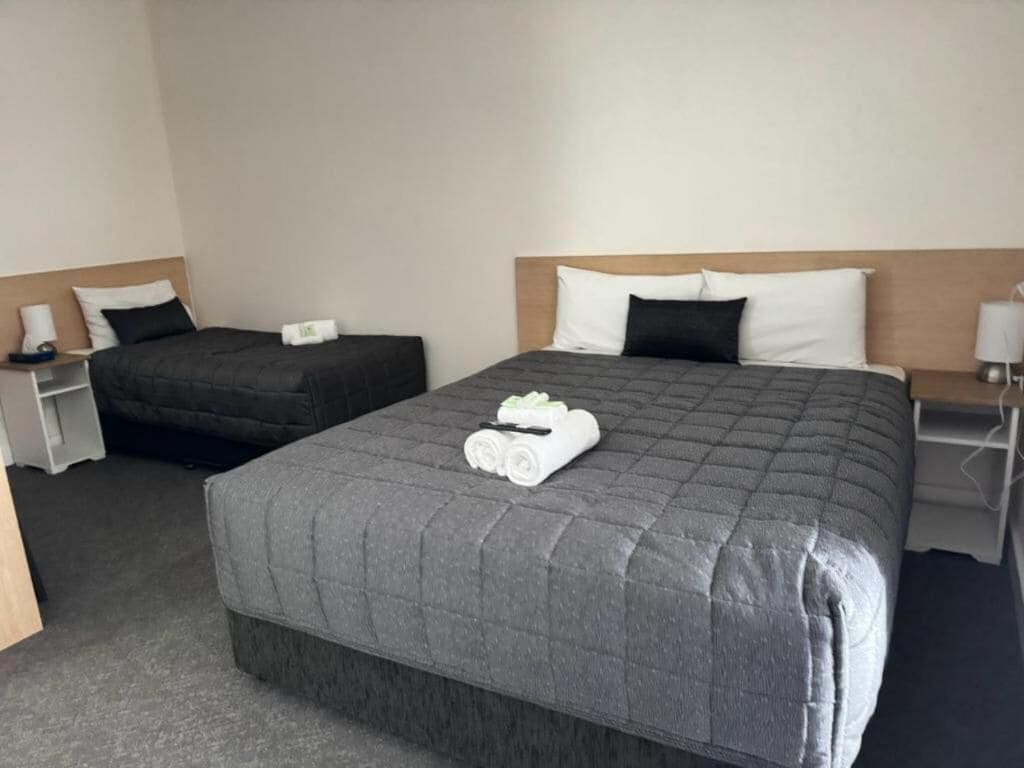 A hotel room with a large bed, a smaller bed, and a nightstand with a lamp.