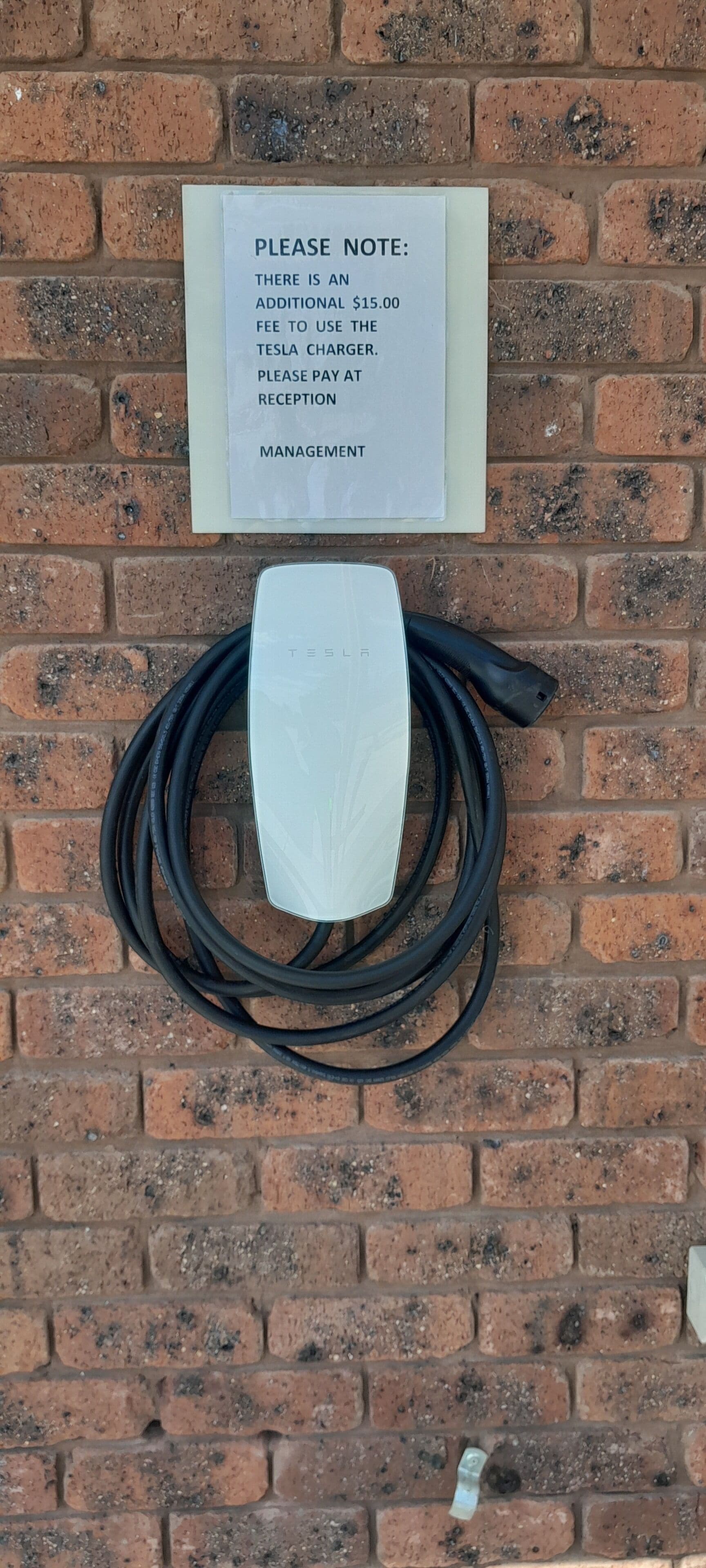 Una estación de carga Tesla con un aviso sobre un cargo adicional de 15,00 dólares.