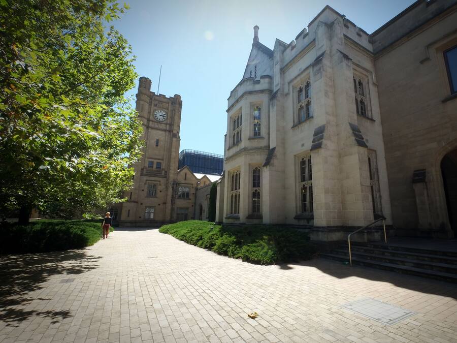 A historic building with a clock tower, paved courtyard, and steps leading to an entrance.