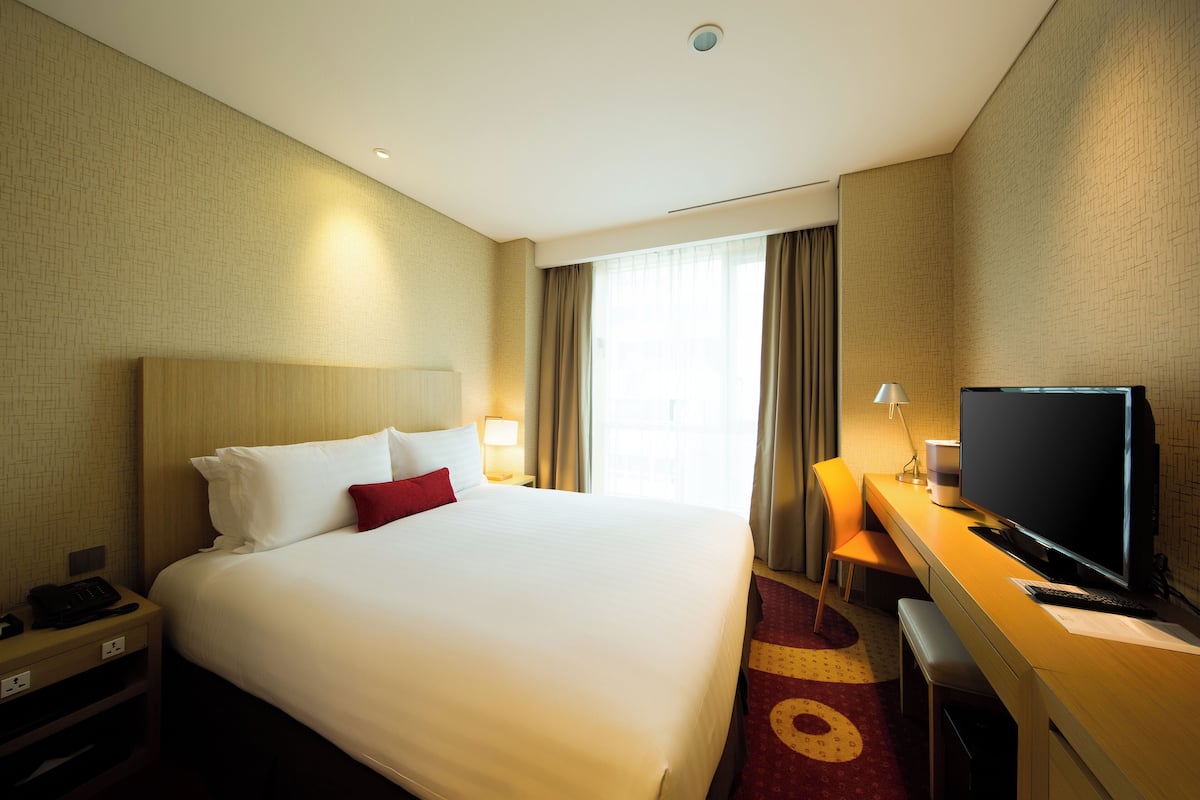 A hotel room with a large bed, a desk with a computer, and a television.