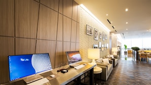 Un moderno vestíbulo de hotel con mostrador de recepción, computadoras y zona de estar.