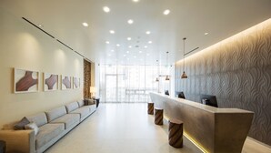 Un área de recepción moderna con un mostrador alargado, un sofá y una pared con diseño.
