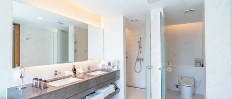Un baño moderno con un espejo grande, lavamanos dobles y ducha con mampara de vidrio.