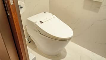 A modern bathroom with a white toilet, marble tiles, and a wooden door frame.