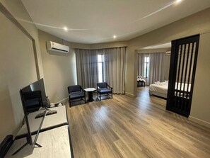 Una habitación de hotel con escritorio, dos sillas, una cama y un televisor.