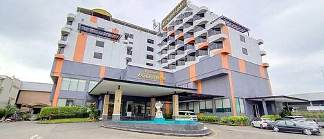 Un hotel de varios pisos con un diseño moderno, que cuenta con una entrada destacada y una estatua en la fachada.
