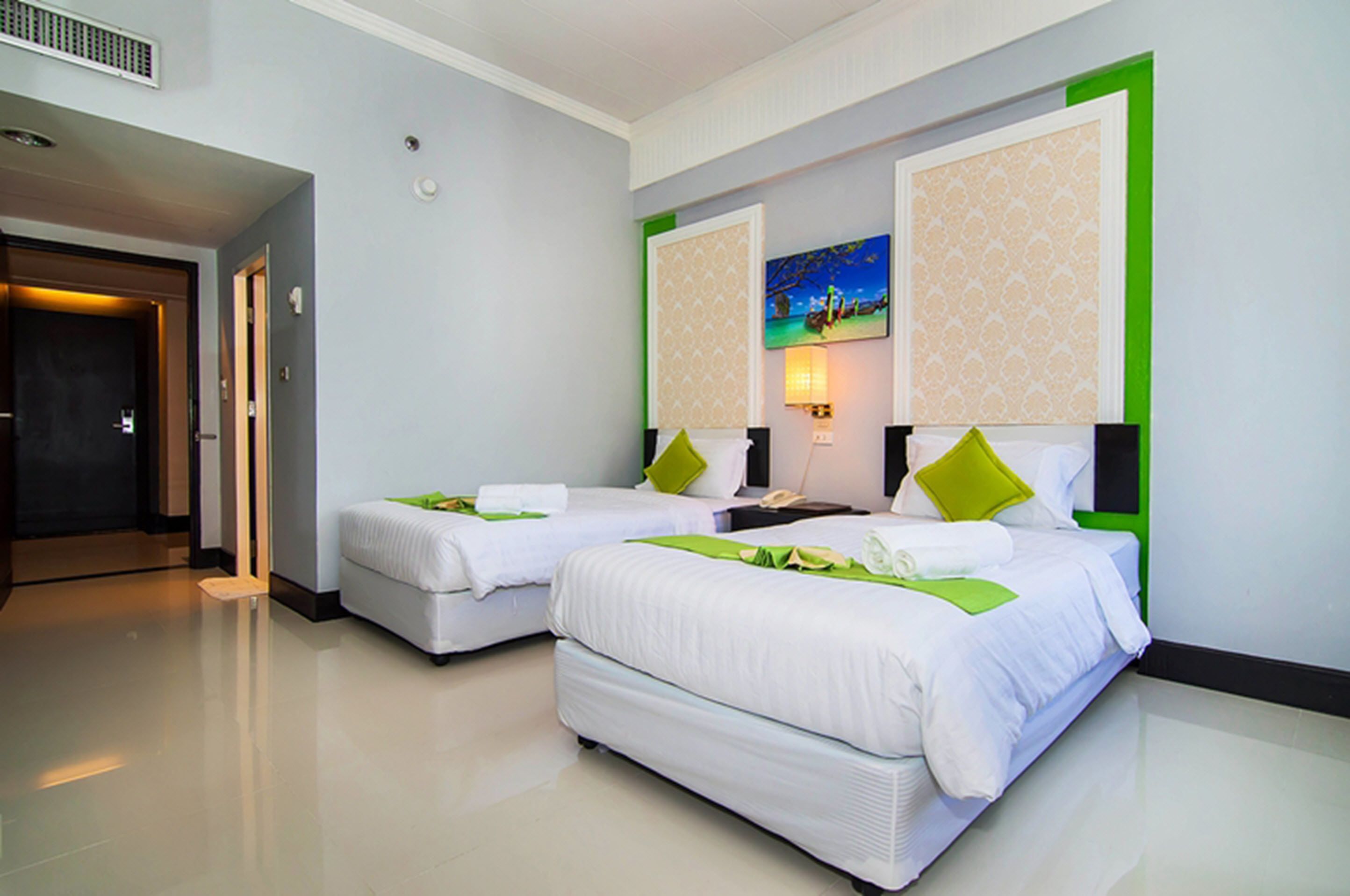 A hotel room with two beds, a nightstand, a lamp, and a painting on the wall.