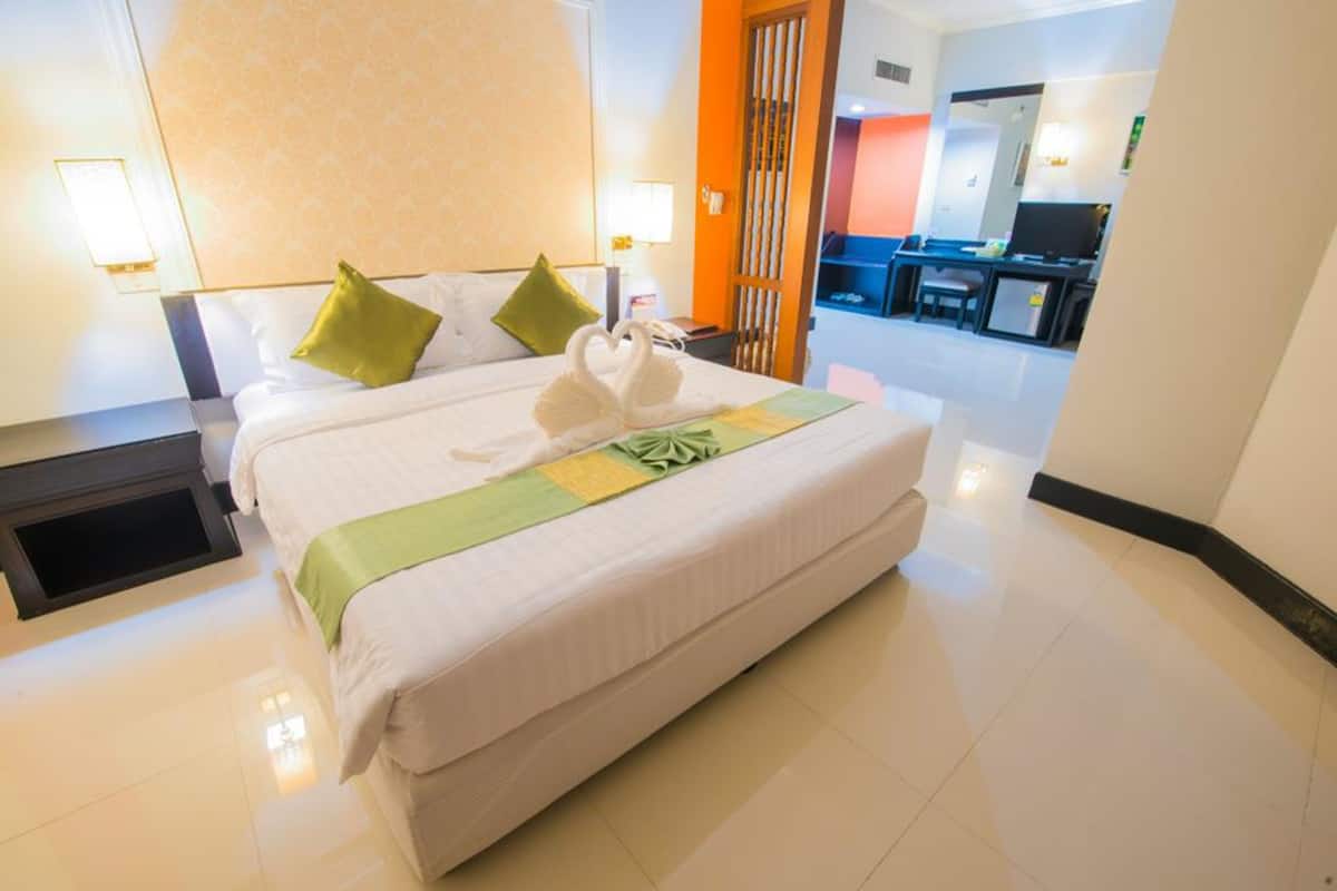Habitación de hotel con una cama grande, dos almohadas, un plaid verde y una almohada con forma de cisne.