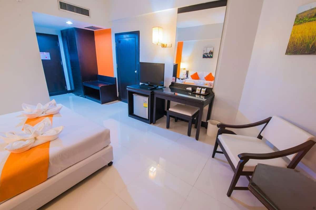 Una habitación de hotel con una cama, un escritorio, una silla y un televisor.