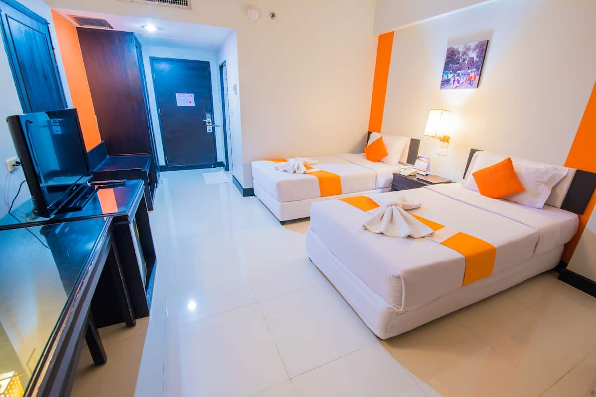 Una habitación de hotel con dos camas, un escritorio con computadora y televisor.