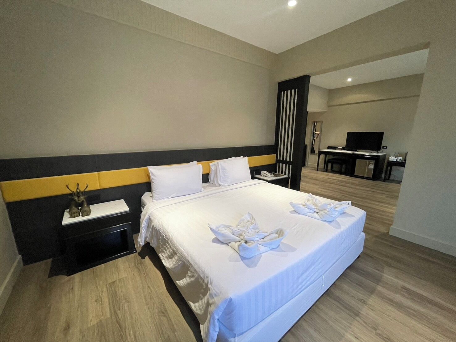 Une chambre d’hôtel avec un grand lit, une table de chevet, un bureau avec une chaise, une télévision et un miroir.