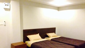 A double bed with a wooden headboard and two pillows, a small wooden nightstand, and a wall-mounted electrical outlet. - Room Riverside (Chiang Mai)