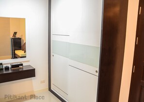 A modern bathroom with a mirror, a dark countertop, and a white door with a glass panel. - Pitikant Place (Lam Luk Ka)
