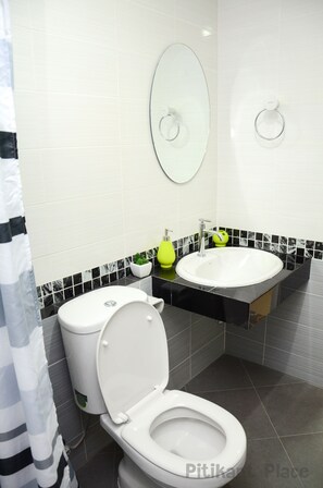 A modern bathroom with a white toilet, a sink, and a mirror. - Pitikant Place (Lam Luk Ka)