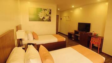 A hotel room with two beds, a desk, a television, and a chair.