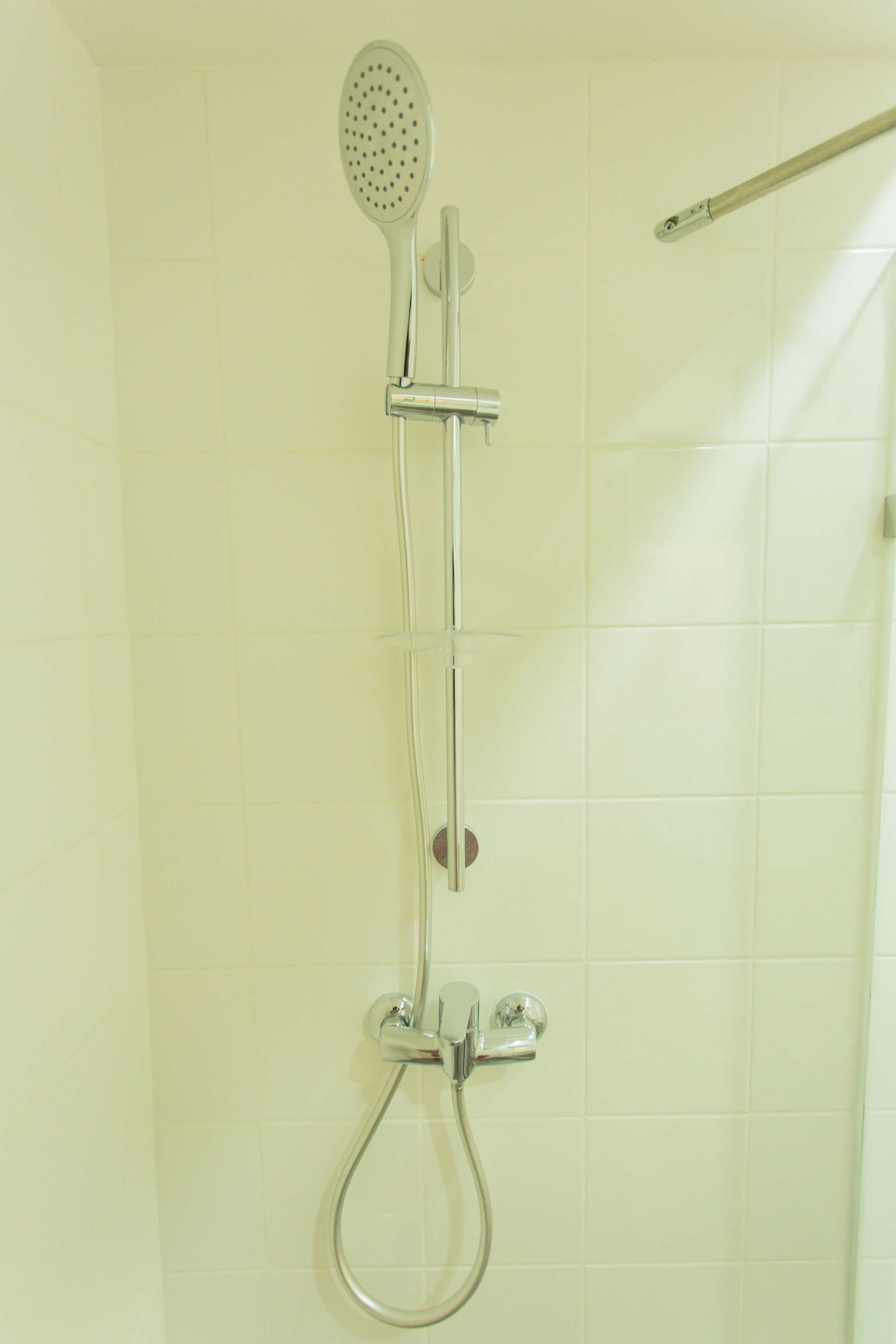 A shower with a handheld showerhead and a handheld shower attachment.