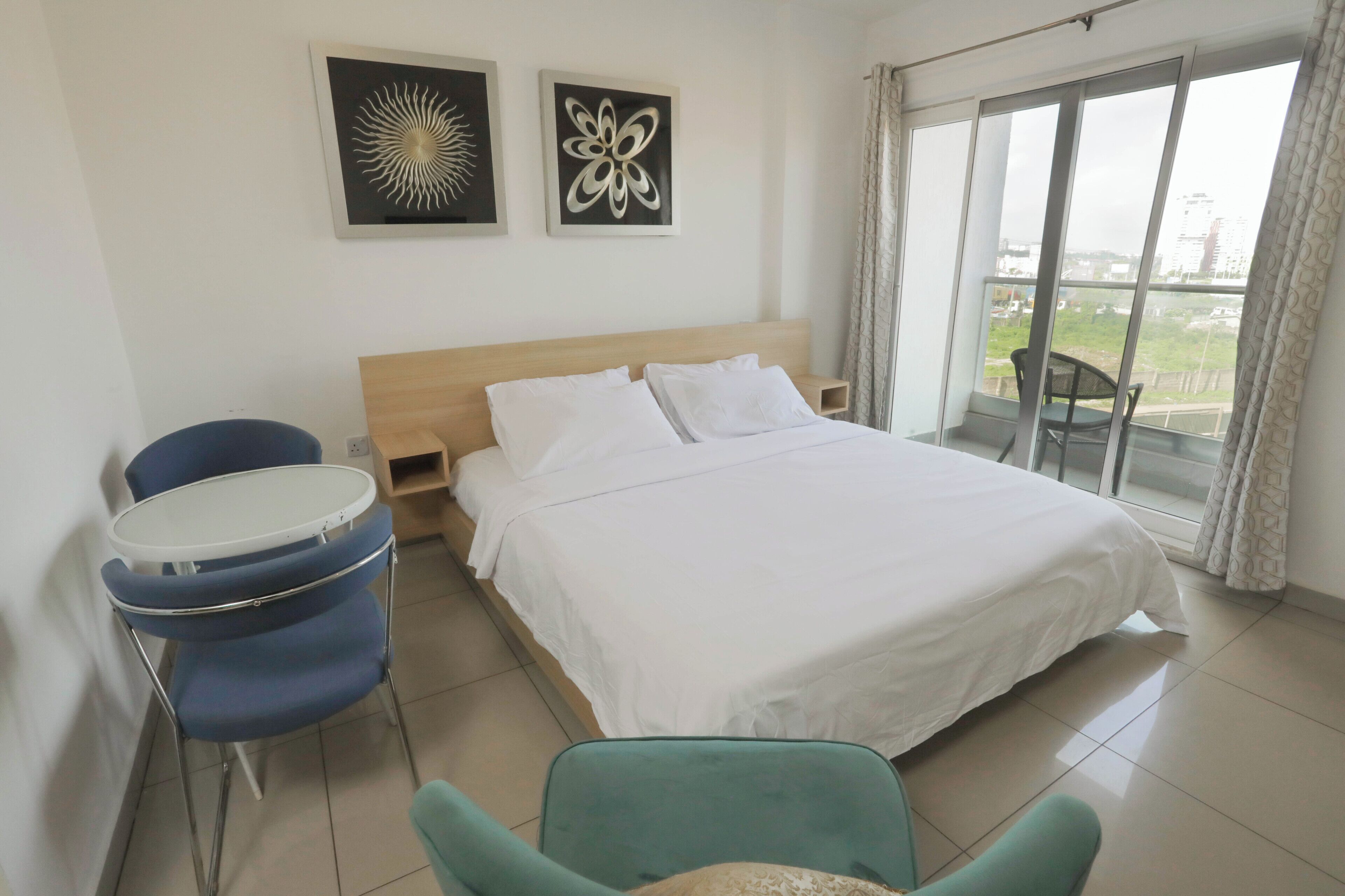 Een hotelkamer met een bed, een tafel, twee stoelen en uitzicht op de stad.