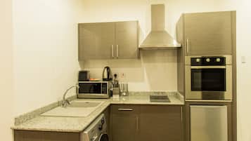 A compact kitchen with a washing machine, microwave, toaster, and built-in oven.