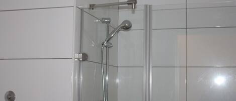 Ducha envuelta en vidrio con cabezal de ducha de mano y grifo empotrado.