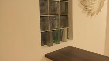 A room with a dark wooden bench, a window with multiple panes, and a decorative wall piece.