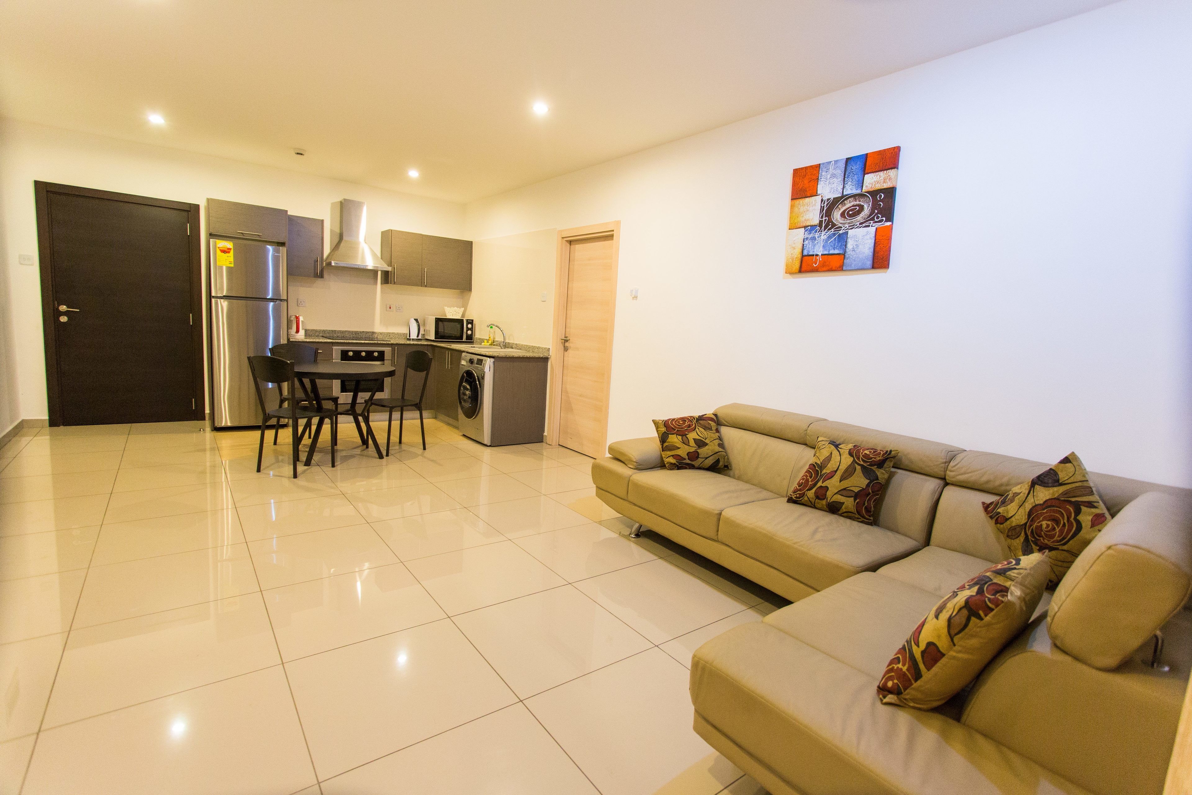 A modern kitchen with a refrigerator, microwave, and washing machine.