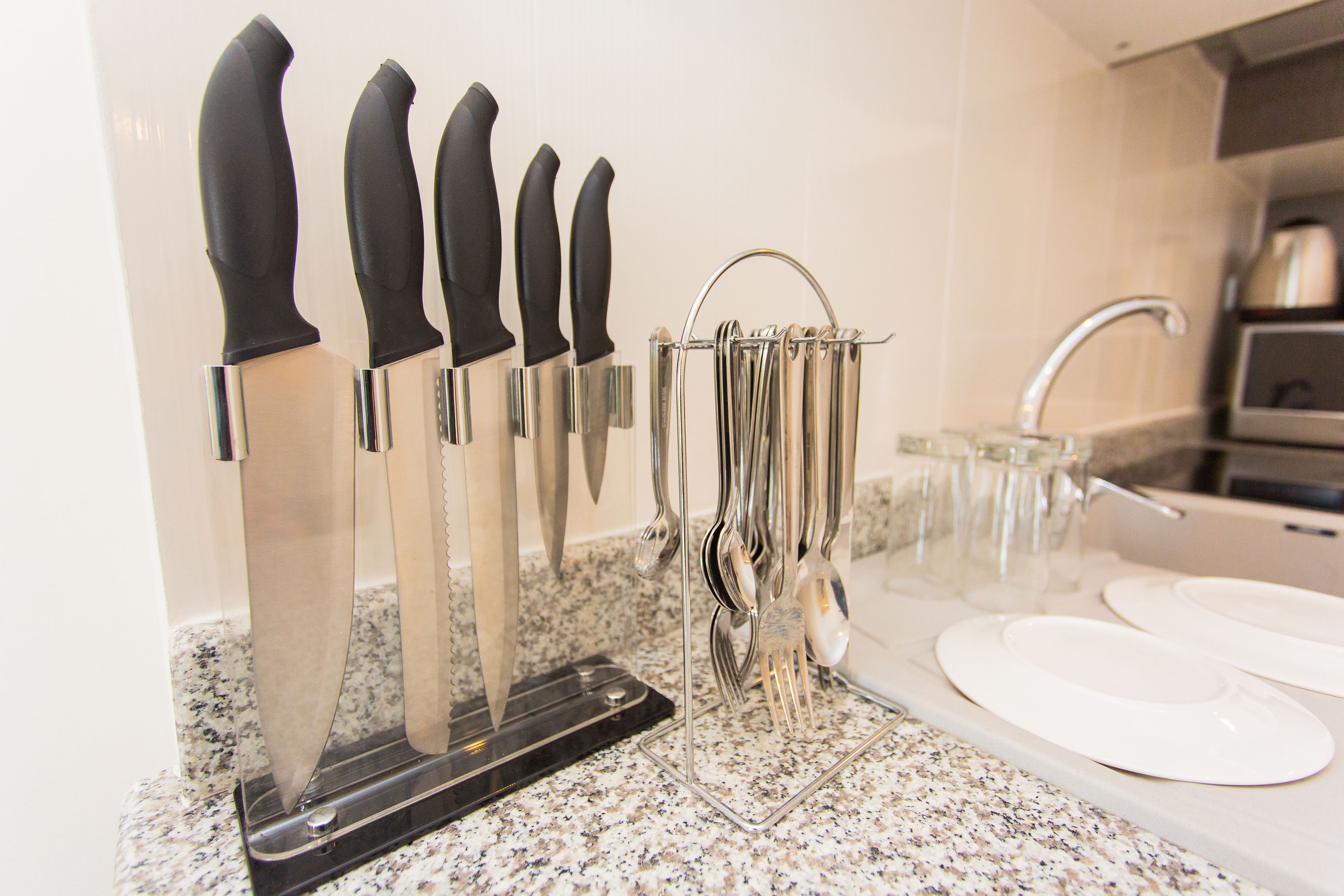 A kitchen counter with a knife block, a glass pitcher, and a sink.